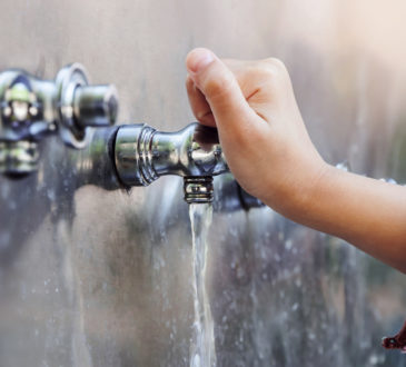 Child's hand with drinking water running from tap water